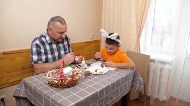 Baba ve oğul Paskalyayı kutluyor. Bir sepet hazırlıyorlar, yumurta boyuyorlar ve eğleniyorlar..