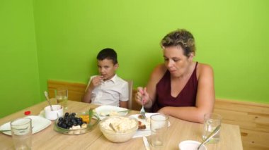 Anne ve oğlu masada otururken salata yiyorlar. Ev yemekleri..