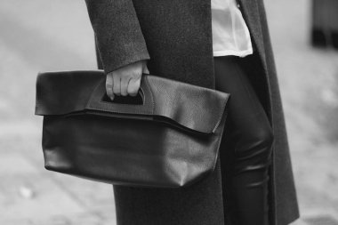 Siyah deri çantalı, yağmurluk giyen bir kadın..