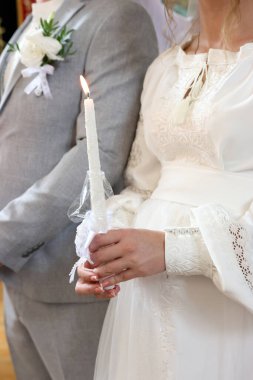 Bir kilise düğünü sırasında, gelin ve damat mum tutarlar..