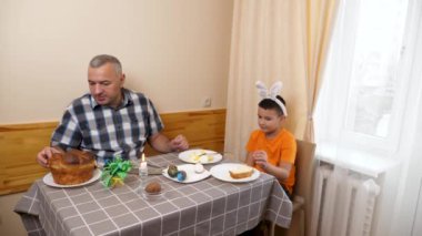 Baba ve oğul Paskalyayı kutluyor. Bir sepet hazırlıyorlar, yumurta boyuyorlar ve eğleniyorlar..