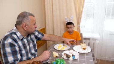 Baba ve oğul Paskalyayı kutluyor. Bir sepet hazırlıyorlar, yumurta boyuyorlar ve eğleniyorlar..