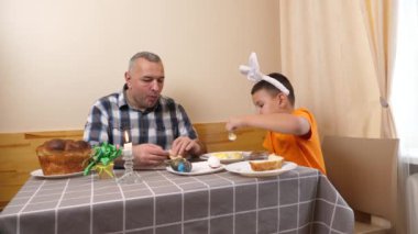 Baba ve oğul Paskalyayı kutluyor. Bir sepet hazırlıyorlar, yumurta boyuyorlar ve eğleniyorlar..