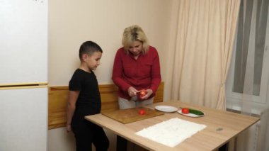 Anne ve oğul sebze doğruyor ve şenlik yemeği için pide ekmeği hazırlıyorlar..