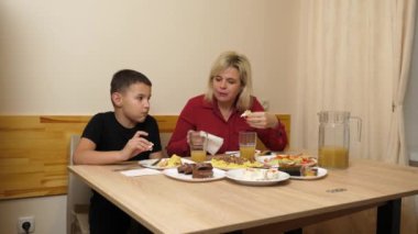 Anne ve oğlu festival masasına oturur ve lezzetli yemeklerin tadını çıkarırlar. Evde kutlarız..