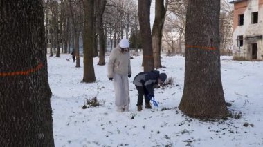 Küçük kardeşiyle bir kız karlı bir parkta yürüyor ve eğleniyor..