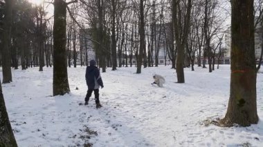 Küçük kardeşiyle bir kız karlı bir parkta yürüyor ve eğleniyor..