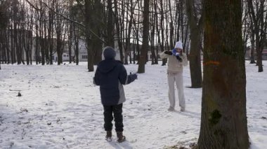 Küçük kardeşiyle bir kız karlı bir parkta yürüyor ve eğleniyor..