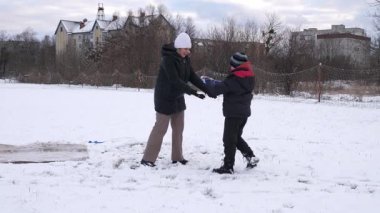 Bir kadın ve oğlu karda halı temizler ve eğlenirler..