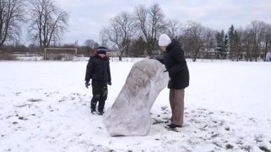 Bir kadın ve oğlu karda halı temizler ve eğlenirler..