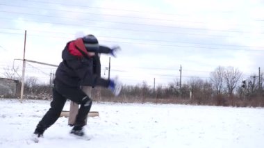 Bir kadın ve oğlu karda halı temizler ve eğlenirler..