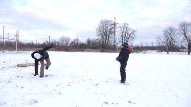 Bir kadın ve oğlu karda halı temizler ve eğlenirler..