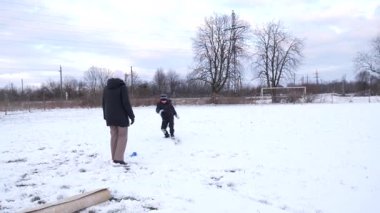 Bir kadın ve oğlu karda halı temizler ve eğlenirler..