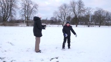 Bir kadın ve oğlu karda halı temizler ve eğlenirler..