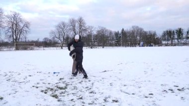 Bir kadın ve oğlu karda halı temizler ve eğlenirler..