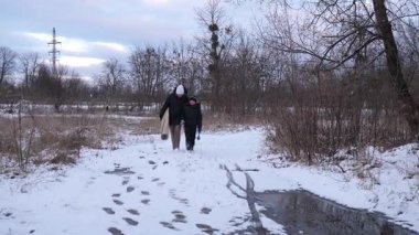 Bir kadın ve oğlu karda halı temizler ve eğlenirler..