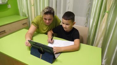 Anne oğluna ev ödevinde yardım eder. Okul eğitimi kavramı.