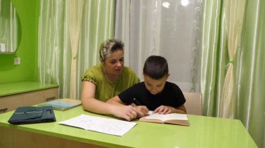 Anne oğluna ev ödevinde yardım eder. Okul eğitimi kavramı.