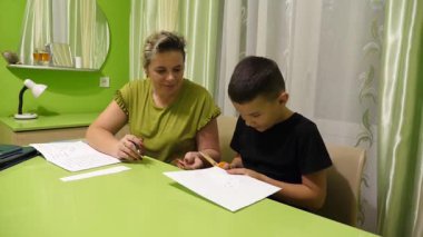 Anne oğluna ev ödevinde yardım eder. Okul eğitimi kavramı.