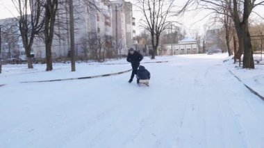 Baba ve oğul kızak kayıyor. Kış eğlencesi.