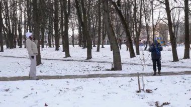 Küçük kardeşiyle bir kız karlı bir parkta yürüyor ve eğleniyor..