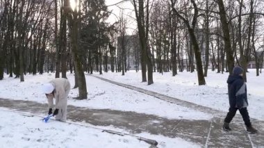 Küçük kardeşiyle bir kız karlı bir parkta yürüyor ve eğleniyor..