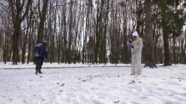 Küçük kardeşiyle bir kız karlı bir parkta yürüyor ve eğleniyor..