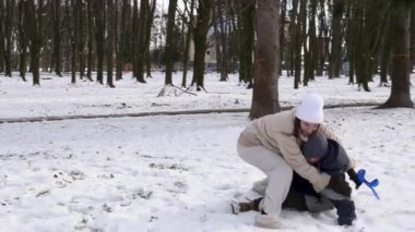 Küçük kardeşiyle bir kız karlı bir parkta yürüyor ve eğleniyor..