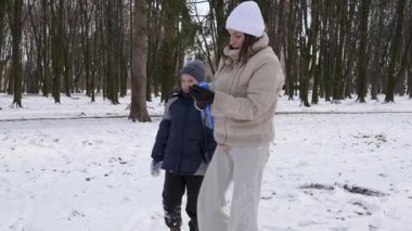 Küçük kardeşiyle bir kız karlı bir parkta yürüyor ve eğleniyor..