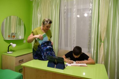 Anne oğluna ev ödevinde yardım eder. Okul eğitimi kavramı.