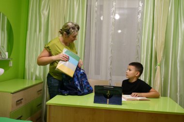 Anne oğluna ev ödevinde yardım eder. Okul eğitimi kavramı.
