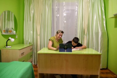 Anne oğluna ev ödevinde yardım eder. Okul eğitimi kavramı.