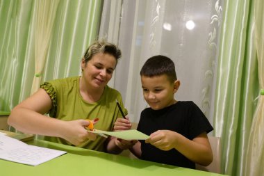 Anne oğluna ev ödevinde yardım eder. Okul eğitimi kavramı.