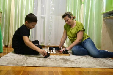 Anne ve oğlu evde satranç oynuyor. Boş zaman ve masa oyunları.