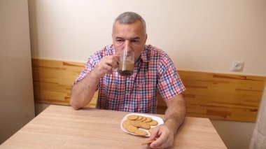 Adam mutfakta kurabiyeyle kahve içiyor..