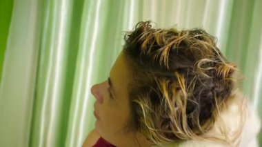 Bir kadın ıslak saçlarını siler ve kurutur..