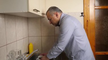 Adam kahvaltıdan sonra bulaşıkları yıkıyor..