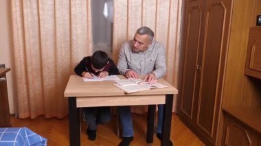 Baba oğluna ev ödevinde yardım ediyor. Ev eğitimi kavramı.