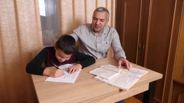 Baba oğluna ev ödevinde yardım ediyor. Ev eğitimi kavramı.