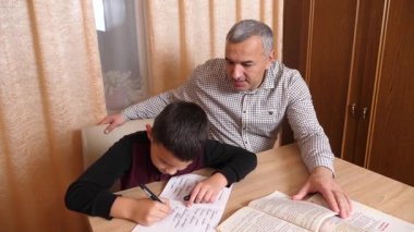 Baba oğluna ev ödevinde yardım ediyor. Ev eğitimi kavramı.