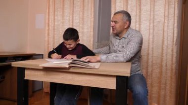 Baba oğluna ev ödevinde yardım ediyor. Ev eğitimi kavramı.