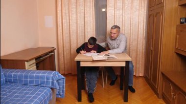 Baba oğluna ev ödevinde yardım ediyor. Ev eğitimi kavramı.