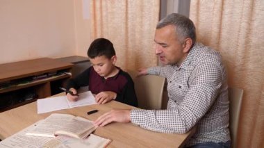Baba oğluna ev ödevinde yardım ediyor. Ev eğitimi kavramı.