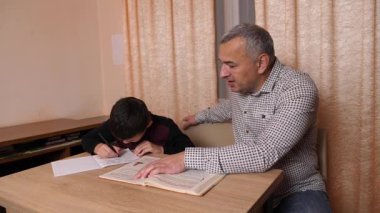 Baba oğluna ev ödevinde yardım ediyor. Ev eğitimi kavramı.
