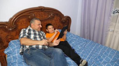 Baba, oğlu yatakta yatarken eğleniyor. Ev eğlencesi..