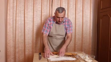 Bir adam hamurdan ve tatlı dolgudan turtalar hazırlar. Ev yapımı yemekler..