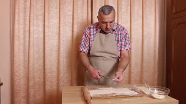 Bir adam hamurdan ve tatlı dolgudan turtalar hazırlar. Ev yapımı yemekler..