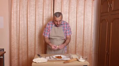 Bir adam hamurdan ve tatlı dolgudan turtalar hazırlar. Ev yapımı yemekler..