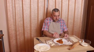 Bir adam hamurdan ve tatlı dolgudan turtalar hazırlar. Ev yapımı yemekler..