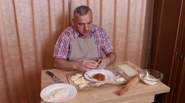 Bir adam hamurdan ve tatlı dolgudan turtalar hazırlar. Ev yapımı yemekler..